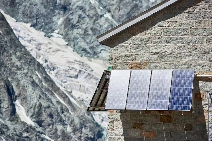 solar panels mounted against the brick wall of a house