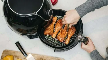 man opening taking roast chicken drumsticks out of air fryer