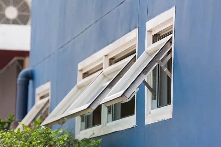 white open windows pictured from outside a building with blue walls